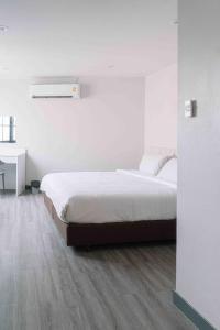 a white bedroom with a bed and a desk at Ma Non Nont Hotel & Apartment in Nonthaburi