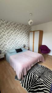 a bedroom with a bed with a pink blanket and a rug at Armorino - Appartement Charmant 2 Chambres - Proximité de tout in Lannion