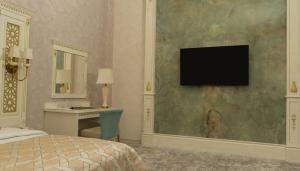 a bedroom with a bed and a desk and a television on a wall at DiliMah Premium Luxury in Samarkand