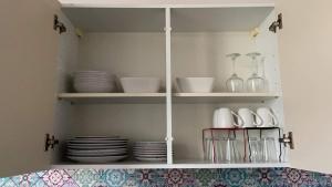 a white cupboard with plates and dishes in it at Armorino - Appartement Charmant 2 Chambres - Proximité de tout in Lannion