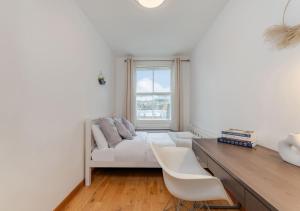 Habitación blanca con sofá, escritorio y ventana en Kensington & Chelsea - Stylish Apartment in Central London, en Londres