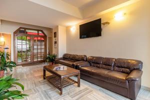 a living room with a leather couch and a tv at Treebo Trend Varuna With Mountain View in Shimla