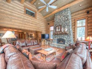uma sala de estar com mobiliário de couro e uma lareira de pedra em MV Big Dog Lodge em Big Sky