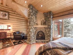 um quarto com uma lareira de pedra num chalé de madeira em MV Big Dog Lodge em Big Sky