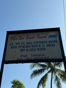 a sign for a beach resort with a palm tree in the background at VILLA SOL BEACH RESORT in Baga