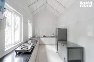 a white kitchen with a refrigerator and a sink at The Mudra Manor 4BR Coorg temperature controlled pool Villa in Madikeri