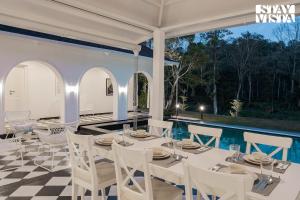 a dining room with a table and chairs on a checkered floor at The Mudra Manor 4BR Coorg temperature controlled pool Villa in Madikeri