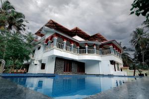 a house with a swimming pool in front of it at Ocean Queen Palace Poovar in Pūvār