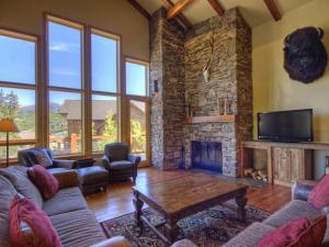 a living room with a stone fireplace and a tv at Black Eagle 32 in Big Sky