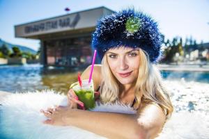 a woman is sitting in the water with a drink at Vila Deluxe - Liptov, Bešeňová in Bešeňová