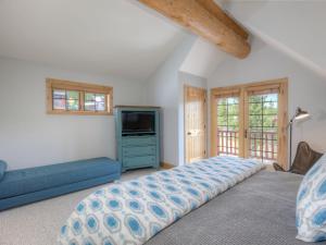 a bedroom with a bed and a blue couch at Powder Ridge Cabin Rosebud 24 in Big Sky