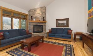 a living room with blue couches and a fireplace at Alpenglow 22B in Big Sky