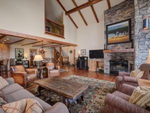 a living room with a stone fireplace and a table at Black Eagle 31 in Big Sky