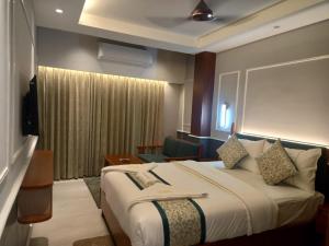 ein Hotelzimmer mit einem großen Bett und einem Stuhl in der Unterkunft Hotel Sonar Bangla Puri in Puri