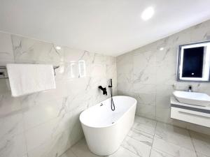 a white bathroom with a toilet and a sink at Riviera Hotel, Apartments & Resorts in Lekki