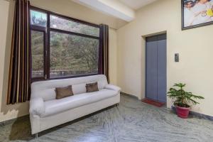 a living room with a couch and a large window at Treebo Trend Shimla Ayurvedic Retreat Kufri in Kūfrī