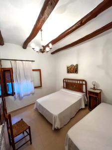 Un dormitorio con 2 camas y una silla. en Casa Rural Nueva Araceli, en Oliete