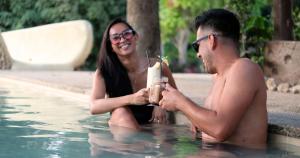 a man and a woman sitting in a swimming pool at Mad Monkey Siquijor in Siquijor