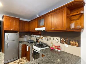 - une cuisine avec des placards en bois et des comptoirs en granit dans l'établissement Ilusión apartment 2 bedroom 1 bathroom, à Baños
