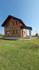 une grande maison en bois dans un champ d'herbe dans l'établissement Vile Plehan, à Derventa