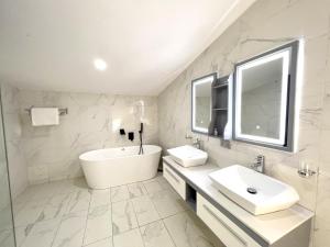 a white bathroom with a tub and a sink at Riviera Hotel, Apartments & Resorts in Lekki