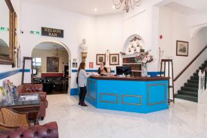 une femme debout à un comptoir bleu dans un salon dans l'établissement Keppels Head Hotel, à Portsmouth