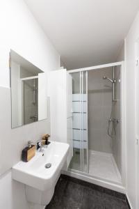 ein weißes Bad mit einer Dusche und einem Waschbecken in der Unterkunft Studio Cosy - proche Paris & Stade de France in Pantin