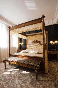 a large bedroom with a canopy bed with a bench at Axelhof Boutique Hotel in Dnipro