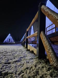 een hek bedekt met sneeuw 's nachts met tenten bij La Căsuțe Luxury in Piatra Neamţ