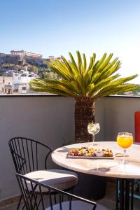 uma mesa com um prato de comida e copos de vinho em Athens Ivy Suites em Atenas