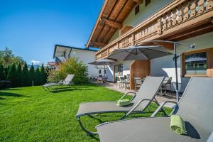 zwei Stühle und ein Regenschirm auf einem Rasen in der Unterkunft Appartement Gamper in Brixen im Thale