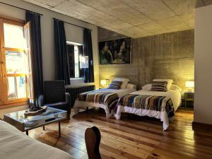 a bedroom with two beds and a chair at Loft Rural LaCalata in Calatañazor