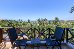 a balcony with two chairs and a view of trees at San Lameer Villa 14205 - 4 Bedroom Luxury - 8 pax -San Lameer Rental Agency in Southbroom