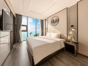 a bedroom with a large bed and a large window at Mangata Beachfront Hotel in Da Nang