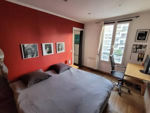 a bedroom with a red wall with a bed and a desk at Buttes Chaumont - Ourcq Canal Paris in Paris