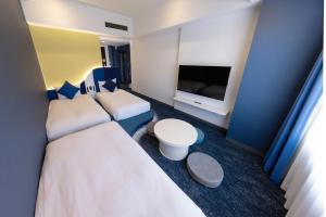 a hotel room with two beds and a flat screen tv at Hotel Keihan Universal Tower in Osaka