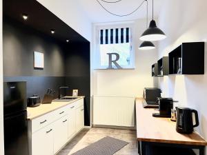 une cuisine avec des placards blancs et un mur noir dans l'établissement MAKERS + ROOMS APARTMENTS, à Detmold
