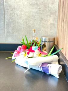 a bouquet of flowers and a bottle on a towel at Studio Hanalei City brand new in the center of Papeete WiFi -Netflix -AC in Papeete