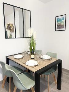 a dining room table with chairs and a bottle of wine at La Douceur de l'Allier, proche gare, avec services premium, by PRIMO C0NCIERGERIE in Moulins