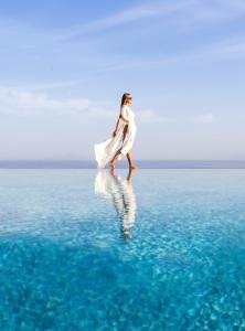 Une femme qui marche sur l'eau dans l'océan dans l'établissement Calme Boutique Hotel - Adults Only, à Drios