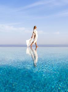 a woman walking on the water in the ocean at Calme Boutique Hotel - Adults Only in Drios