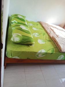 Sungaitutung的住宿－Natural hot spring homestay，一张带绿色床单和白色鲜花的床