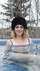 a woman in a swimming pool wearing a hat at Cottage with Glass Bubble and Hot tub in Reykholt