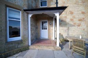 eine weiße Tür zu einem Backsteingebäude mit einer Bank in der Unterkunft Signal Point Cottage in Ventnor