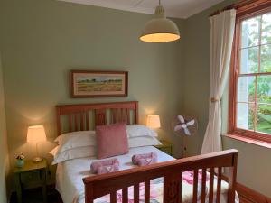 a bedroom with a bed with white sheets and pink pillows at Rosehaven Cottage in Swellendam