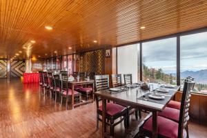 a dining room with tables and chairs and a large window at Treebo Trend Snow View Resort Kufri With Mountain View in Shimla