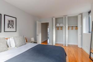 a white bedroom with a large bed and wooden floors at Midtown 2br w doorman nr theater district NYC-1349 in New York