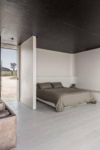 1 dormitorio con 1 cama en una pared blanca en Zensi Retreat - Villa, en Eurunderee