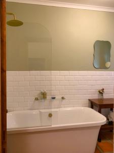 a white bath tub in a bathroom with a mirror at Rosehaven Cottage in Swellendam