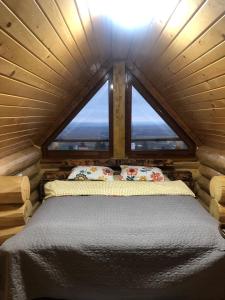 a bedroom in a log cabin with a large window at Casa din Deal in Moldoveneşti